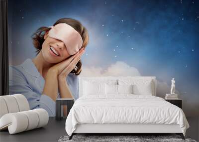 people and bedtime concept - happy young woman in pajama and eye sleeping mask over starry night sky and cloud background Wall mural