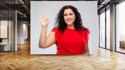 people and gesture concept - happy woman in red dress waving hand over grey background Wall mural