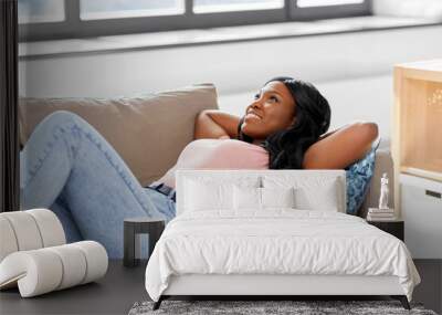 people and leisure concept - happy african american young woman lying on sofa at home Wall mural