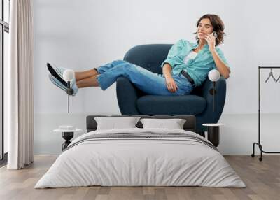 people and technology concept - portrait of happy smiling young woman sitting in modern armchair and calling on smartphone over grey background Wall mural