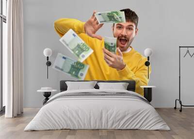 people concept - happy young man in yellow sweatshirt pouring money over grey background Wall mural