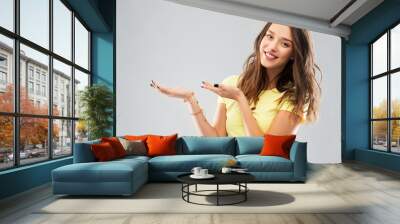 people concept - smiling young woman or teenage girl in blank yellow t-shirt holding something imaginary over grey background Wall mural