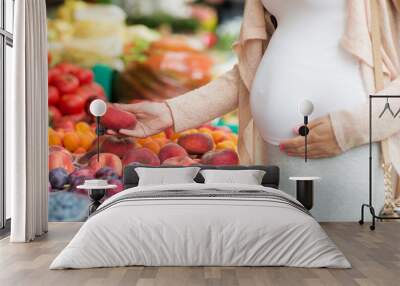 pregnant woman choosing fruits at street market Wall mural