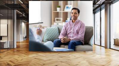 psychology, mental therapy and people concept - happy smiling young indian man patient and woman psychologist at psychotherapy session Wall mural