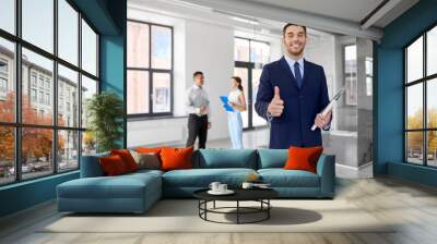 real estate business, sale and people concept - happy smiling realtor or businessman with folder showing thumbs up and customers at new office room Wall mural