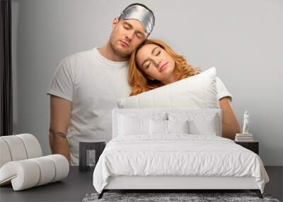 relationships and people concept - couple in white t-shirts with eye sleeping mask and pillow over grey background Wall mural