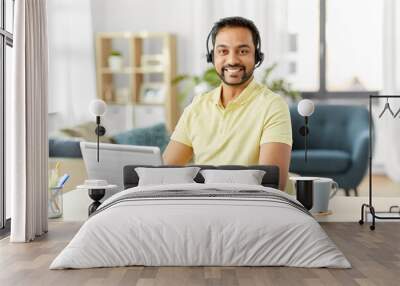 remote job, technology and people concept - happy smiling indian man with headset and laptop computer having conference call at home office Wall mural