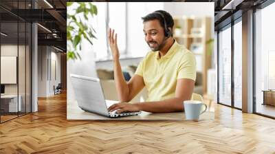 remote job, technology and people concept - happy smiling indian man with headset and laptop computer having conference call at home office Wall mural