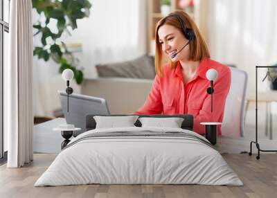 remote job, technology and people concept - happy smiling young woman with headset and laptop computer having video conference at home office Wall mural