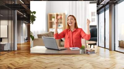 remote job, technology and people concept - happy smiling young woman with laptop computer working at home office and celebrating success Wall mural