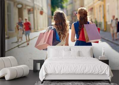 sale, consumerism and people concept - young women with shopping bags walking along city street Wall mural