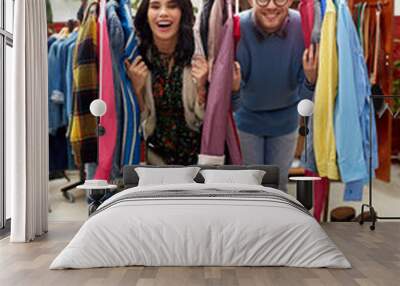 sale, shopping, fashion and people concept - happy couple having fun at vintage clothing store hanger Wall mural