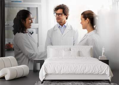 science, work and people concept - international group of happy scientists shaking hands in laboratory Wall mural