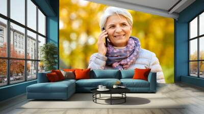 season, communication and people concept - happy senior woman calling on smartphone at autumn park Wall mural