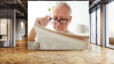 senior man in glasses reading newspaper at home Wall mural