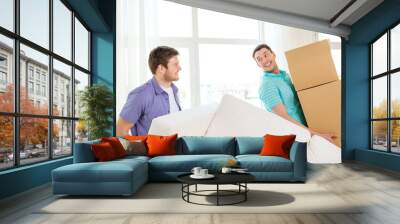 smiling friends with sofa and boxes at new home Wall mural