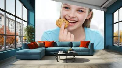 smiling little girl eating cookie or biscuit Wall mural