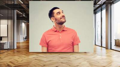 smiling man looking up over gray background Wall mural