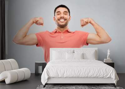 smiling man showing biceps over gray background Wall mural