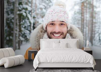 smiling young man in snowy winter forest Wall mural