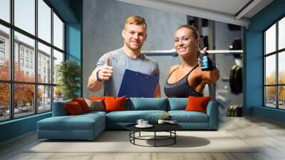 smiling young woman with personal trainer in gym Wall mural