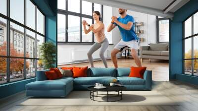 sport, fitness, lifestyle and people concept - smiling man and woman exercising and doing squats at home Wall mural