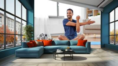 sport, fitness and healthy lifestyle concept - indian man training and stretching arm at home Wall mural