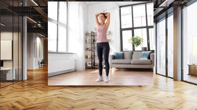 sport, fitness and healthy lifestyle concept - smiling young woman stretching arms at home Wall mural