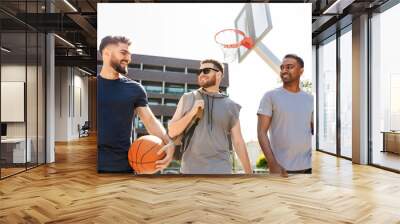 sport, leisure games and male friendship concept - group of men or friends going to play basketball outdoors Wall mural