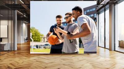 sport, leisure games and male friendship concept - group of men or friends with smartphone at outdoor basketball playground Wall mural