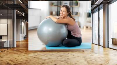 sport and healthy lifestyle concept - happy smiling young woman with fitness ball at home Wall mural