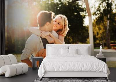 summer holidays, love and people concept - happy young couple with ball having fun on basketball playground Wall mural