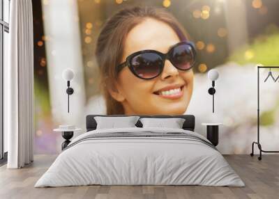 summertime, leisure and people concept - portrait of happy young woman in sunglasses at summer garden Wall mural