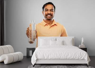 sustainability, consumerism and eco friendly concept - happy smiling indian man showing water in reusable glass bottle grey background Wall mural