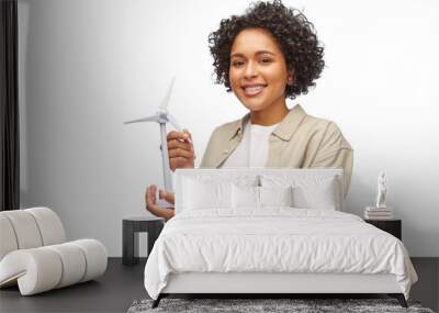 sustainable energy, power and people concept - happy smiling woman holding toy wind turbine over white background Wall mural