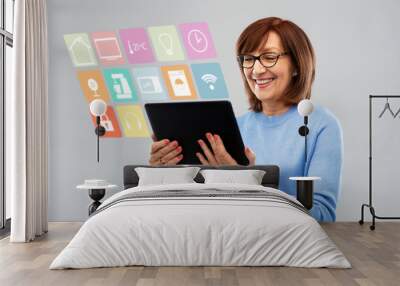 technology, automation and internet of things concept - smiling senior woman in glasses with tablet computer using smart home app over grey background Wall mural