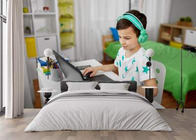 technology, gaming and people concept - boy in headphones playing video game on laptop computer at home Wall mural