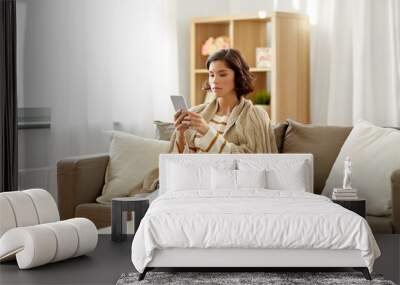 technology, health and cold concept - sad sick woman in blanket using smartphone at home Wall mural