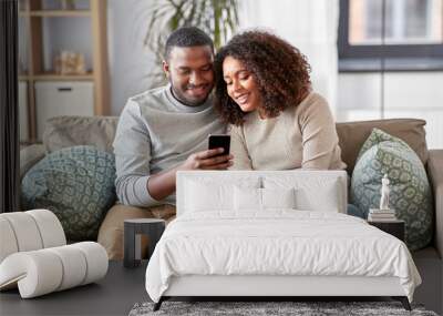 technology, internet and people concept - happy african american couple with smartphone at home Wall mural