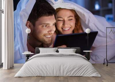 technology, internet and people concept - happy couple using tablet pc computer in bed at night Wall mural