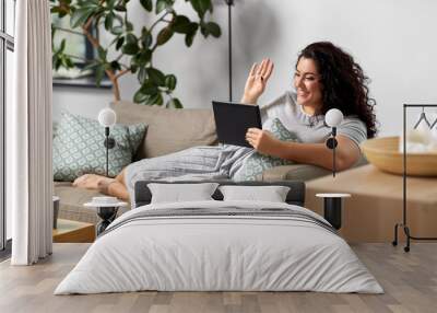 technology, leisure and people concept - happy smiling woman with tablet pc computer having video chat and waving hand at home Wall mural