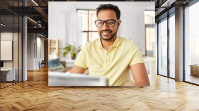 technology, remote job and lifestyle concept - happy indian man in glasses with laptop computer working at home office Wall mural