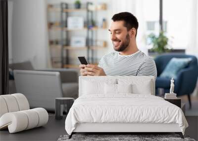 technology, remote job and people concept - happy smiling man with smartphone and laptop computer working at home office Wall mural