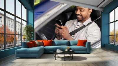 transport, people and technology concept - smiling indian man or driver using smartphone in car Wall mural