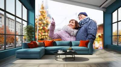 travel, tourism, holidays and people concept - happy senior couple hugging at christmas market on town hall square in tallinn, estonia Wall mural