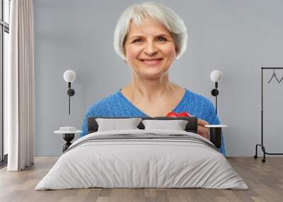 valentine's day, health and old people concept - portrait of smiling senior woman with red heart over grey background Wall mural