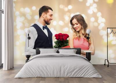 valentines day, couple, relationships and people concept - happy man giving woman flowers and present over beige background and festive lights Wall mural