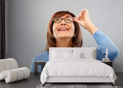 vision and old people concept - portrait of smiling senior woman in glasses looking up over grey bac Wall mural