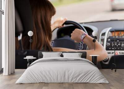 woman driving a car and looking at watch Wall mural