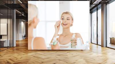 young woman with lotion washing face at bathroom Wall mural